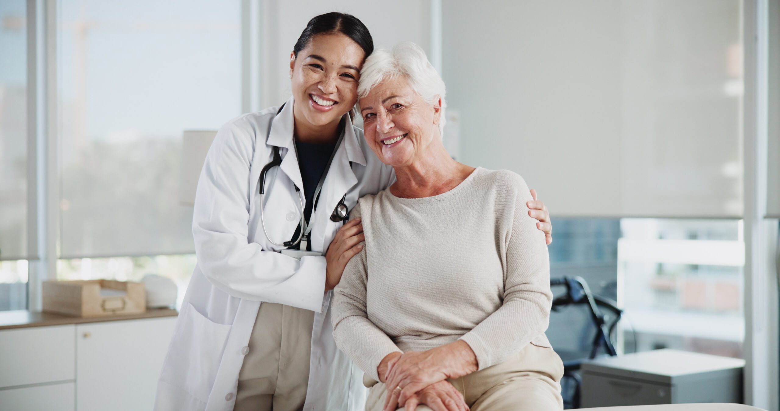 Senior woman, doctor and hug in portrait at clinic with support, kindness and medical services. People, elderly patient and embrace with healthcare, happy and together for consulting at hospital.